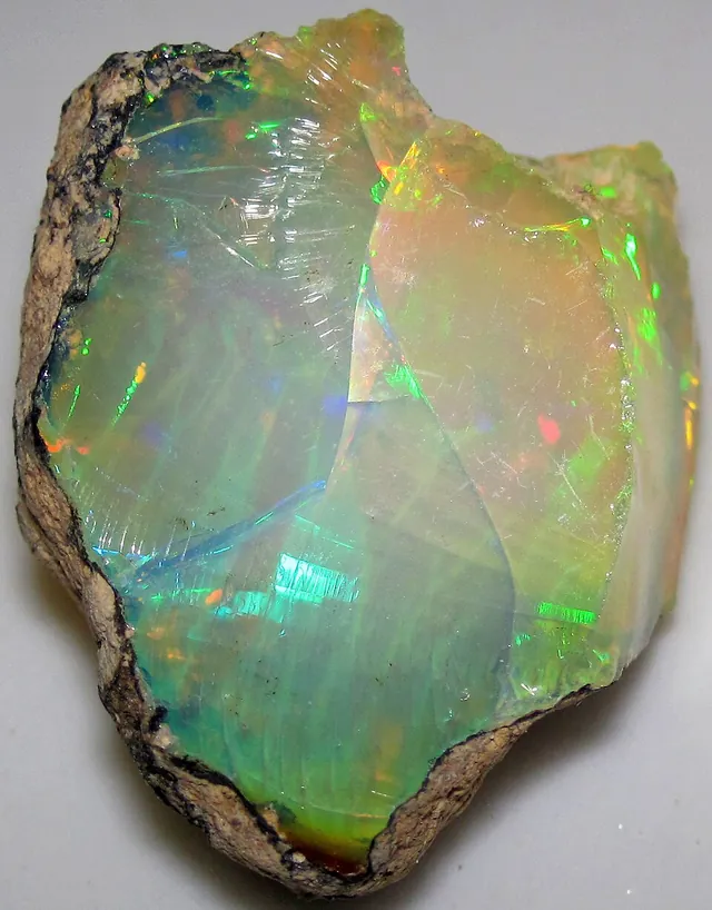 Opale noble (SiO₂·nH₂O) : minéral de la famille « oxydes et hydroxydes », système amorphe, dureté 5,5 à 6,5 (Mohs), couleurs : blanc laiteux, noir, bleu gris, à reflets multicolores